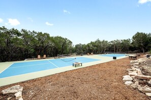 An outdoor tennis court with seating and a net. - A Romantic Getaway in this Luxurious Yurt for Couples in Wimberley, TX (Wimberley)