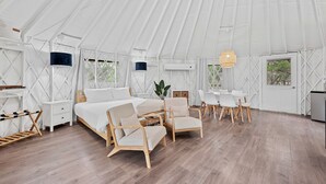 A tent-style room with a bed, chairs, a table, and a hanging light fixture. - A Romantic Getaway in this Luxurious Yurt for Couples in Wimberley, TX (Wimberley)