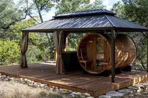 A wooden structure with a metal roof, a wooden barrel-shaped room, and a wooden deck. - A Romantic Getaway in this Luxurious Yurt for Couples in Wimberley, TX (Wimberley)