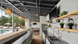 Une cuisine moderne avec des plans de travail en bois, des luminaires suspendus et des plantes en pot.