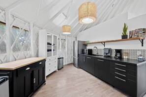 A modern kitchen with a wooden countertop, black cabinets, a built-in microwave, and a hanging light fixture. - A Romantic Getaway in this Luxurious Yurt for Couples in Wimberley, TX (Wimberley)