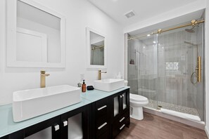 A modern bathroom with two sinks, a toilet, and a glass-enclosed shower. - A Romantic Getaway in this Luxurious Yurt for Couples in Wimberley, TX (Wimberley)