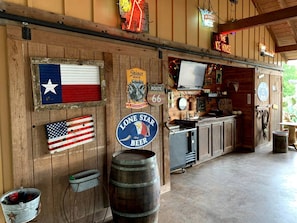 Eine rustikale Bar mit Holzwänden, einem Neon-Schild für 'The Ice House' und einem Schild für 'Lone Star Beer'.