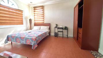 Un dormitorio con cama, escritorio, armario y ventana con persianas.
