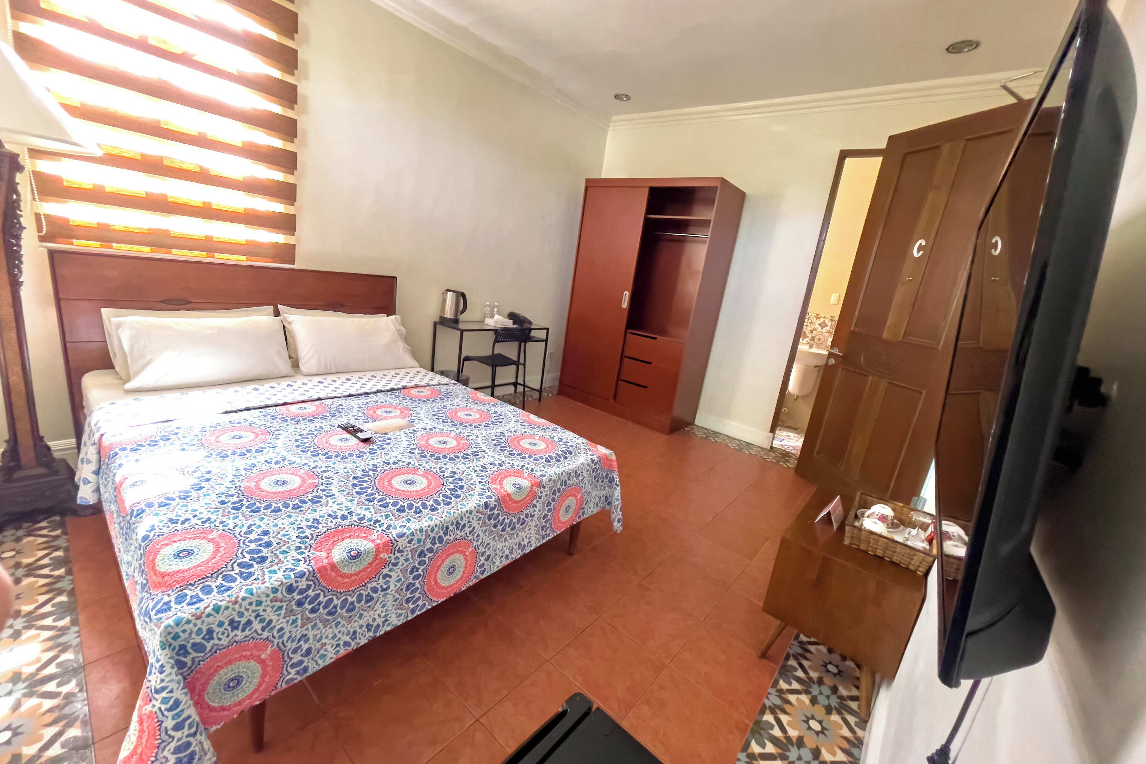 Ein Hotelzimmer mit Bett, Schreibtisch, Kleiderschrank und Fernseher.