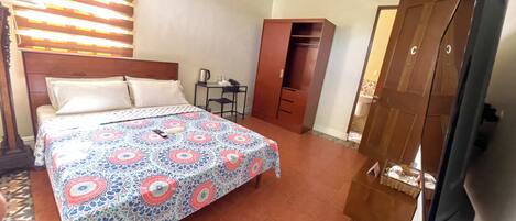 Ein Hotelzimmer mit Bett, Schreibtisch, Kleiderschrank und Fernseher.
