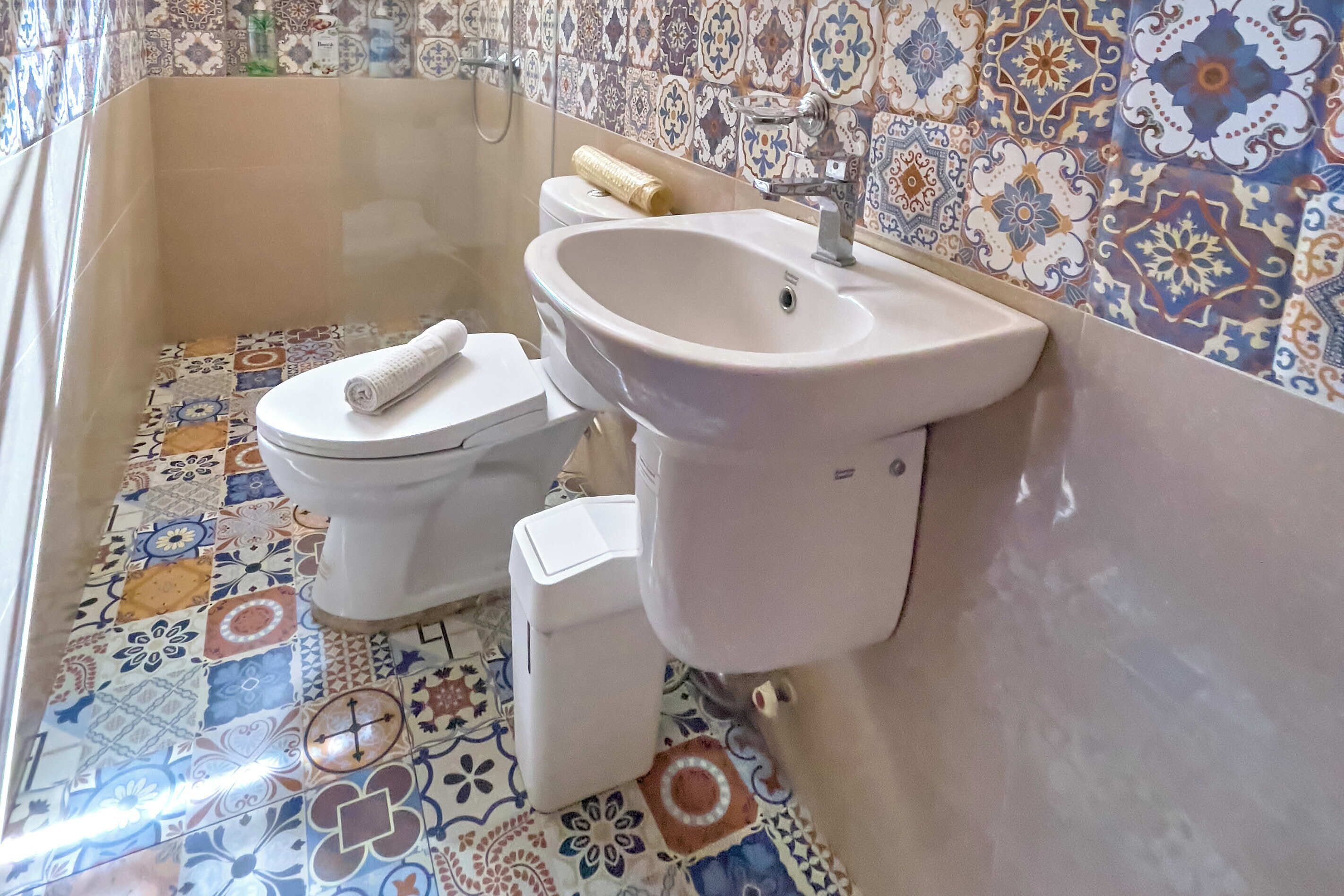 A bathroom with a toilet, sink, and shower area.