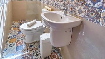 A bathroom with a toilet, sink, and shower area.