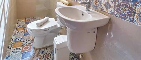 A bathroom with a toilet, sink, and shower area.