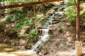 A natural waterfall with a wooden bridge overhead.