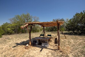Ein rustikaler Essbereich im Freien mit einer Holz-Pergola, einem Tisch und zwei Stühlen.