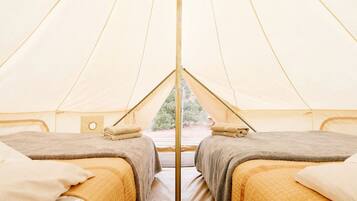 A tent with two beds, a central pole, and a window.