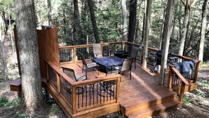 A wooden deck with outdoor furniture, surrounded by trees. - Magical Tree House Rental in the Woods near Syracuse for Glamping in New York State (Lafayette)