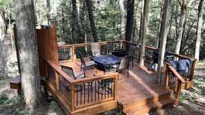 A wooden deck with outdoor furniture, surrounded by trees.