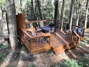 A wooden deck with outdoor furniture, surrounded by trees.