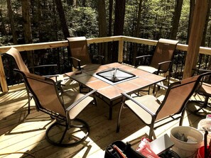 A wooden deck with a table and chairs, surrounded by trees.