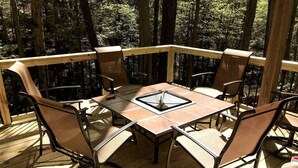 A wooden deck with a table and chairs, surrounded by trees. - Magical Tree House Rental in the Woods near Syracuse for Glamping in New York State (Lafayette)