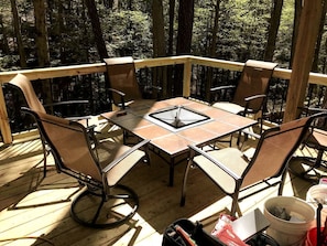 A wooden deck with a table and chairs, surrounded by trees.