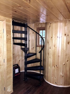 A wooden interior with a black spiral staircase.