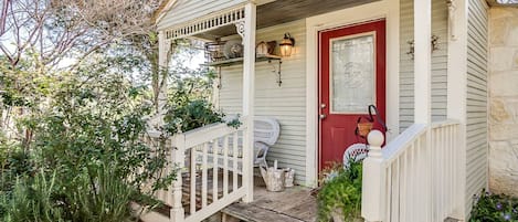 A house with a porch, a red door, and a small garden.
