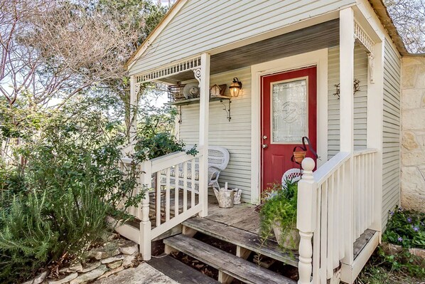A house with a porch, a red door, and a small garden.