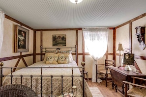 Quarto com cama, escrivaninha, cadeira, luminária e um quadro na parede.
