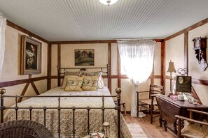 Quarto com cama, escrivaninha, cadeira, luminária e um quadro na parede.