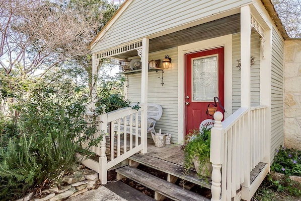 A house with a porch, a red door, and a small garden.