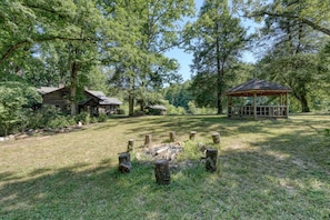 Un chalet rustique doté d’une terrasse en bois, entouré d’une forêt dense et surplombant un ciel dégagé.