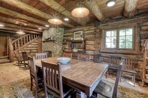 A rustic log cabin interior with a stone fireplace, wooden dining table, and a staircase. - Newly Restored Cabin in Dahlonega, Georgia, Surrounded by Wineries and Cozy Nature (Dahlonega)