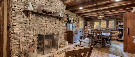 A rustic interior with a stone fireplace, wooden furniture, and a dining area.