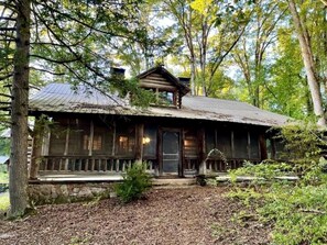 Eine rustikale Holzhütte mit Steinunterbau und einer Veranda mit Geländer.