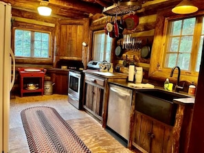 Une cuisine rustique avec des meubles en bois, un poêle, un évier et des casseroles suspendues.
