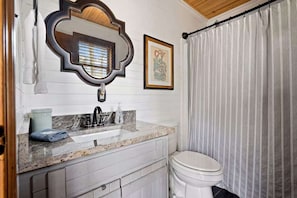 A bathroom with a sink, mirror, toilet, and a shower curtain.