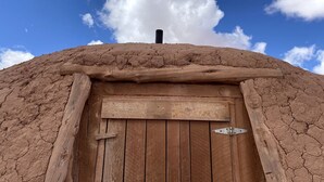 A rustic wooden door with a metal latch, set in a weathered wall with a rough texture. - Traditional Navajo Hut Rental for a Secluded Vacation near Page, Arizona (Page)