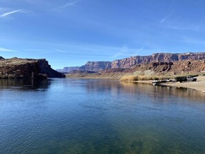 Une rivière paisible aux eaux claires, bordée de falaises rocheuses et d’une végétation clairsemée.
