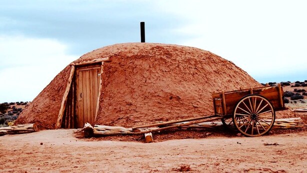 A traditional structure with a wooden door and a wheelbarrow. - Traditional Navajo Hut Rental for a Secluded Vacation near Page, Arizona (Page)