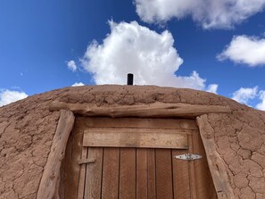 Una puerta de madera rústica con un pestillo de metal, ubicada en un muro desgastado de textura rugosa.