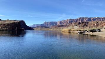A calm river with clear water, surrounded by rocky cliffs and sparse vegetation.