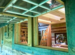 A wooden cabin with a window featuring triangular cutouts and a view of a mural.