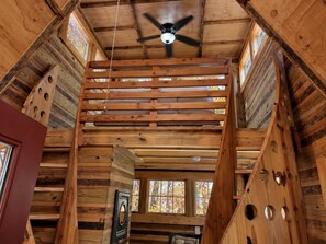A wooden interior with a ceiling fan, wooden beams, and a window with stained glass.