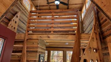 A wooden interior with a ceiling fan, wooden beams, and a window with stained glass.