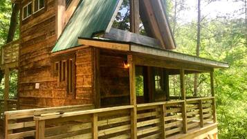 Een houten chalet met een balkon, een schuin dak en een raam.