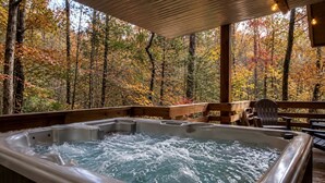 A hot tub with a wooden deck and chairs, surrounded by a forest with autumn foliage. - Charming Tree House with a Hot Tub in Chattahoochee National Forest, Georgia (Suches)