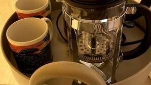 Una cafetera amb un recipient transparent i una tapa negra, acompanyada de dues tasses amb un disseny de tortuga.
