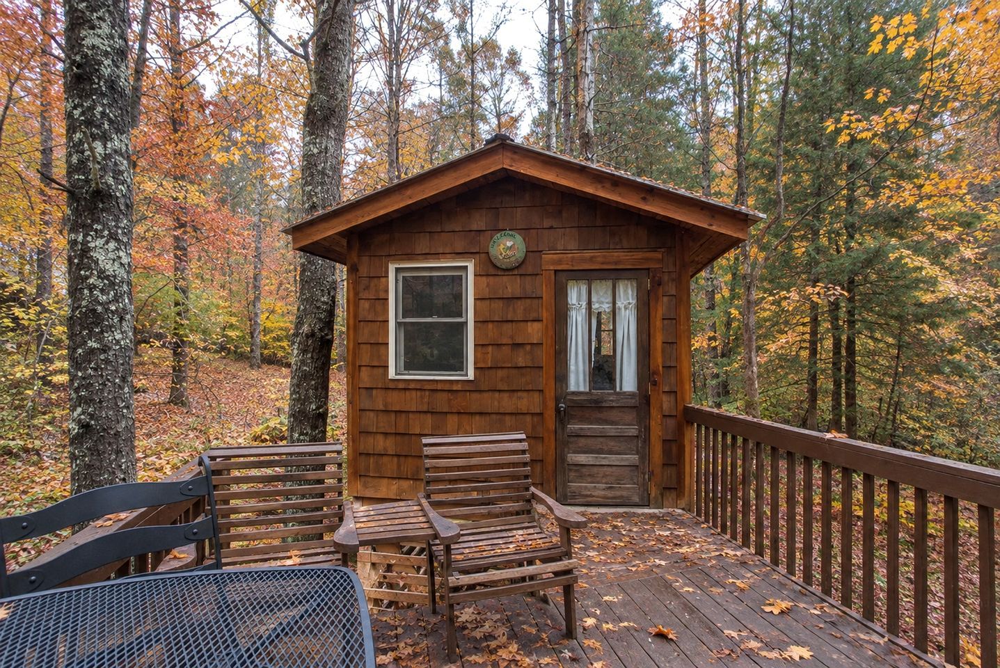 A wooden cabin with a porch, two benches, and a table.