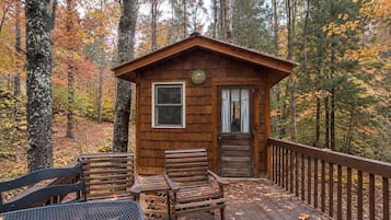 Una cabaña de madera con un porche, dos bancos y una mesa.