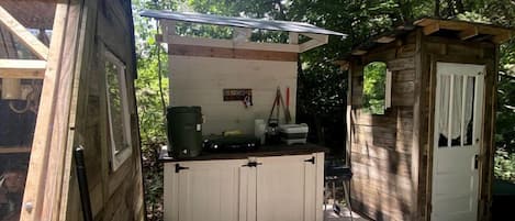 A wooden deck with a small kitchen area, a trash bin, and a door.