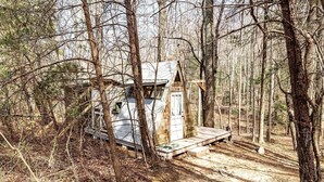 A small cabin in a forest with a wooden deck and a door. - Off-Grid Experience in Cozy Mini A-Frame in Picturesque Tennessee (Grandview)