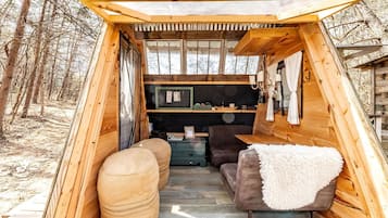 A wooden cabin interior with a sofa, ottoman, and a small table.